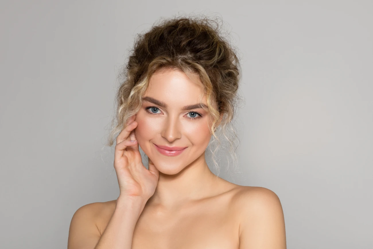 Portrait of sensual beautiful young woman posing on grey studio background, enjoying her smooth glow face skin